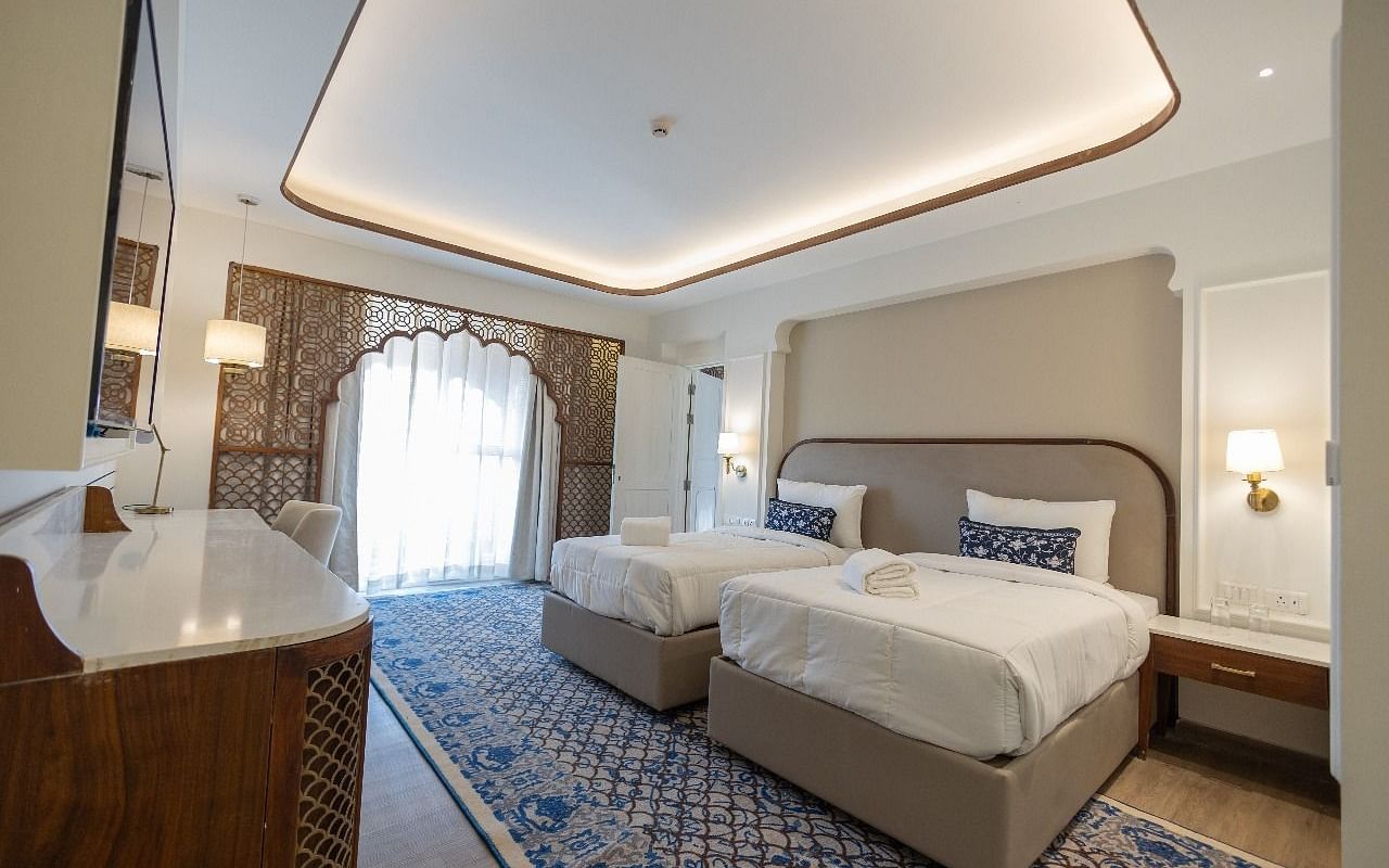 Full view image of the Jalrupa Room with a twin bed with ample of natural light coming from the balcony covered with linen curtains at Bhagirathi by RDB Atishay.
