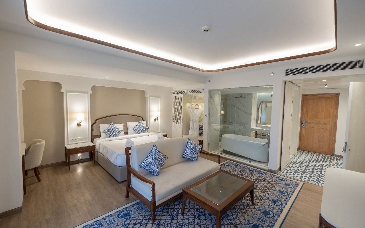 Full view shot of the Purna Room at Bhagirathi by RDB Atishay featuring a double bed and a couch in front of it at Bhagirathi by RDB Atishay. 