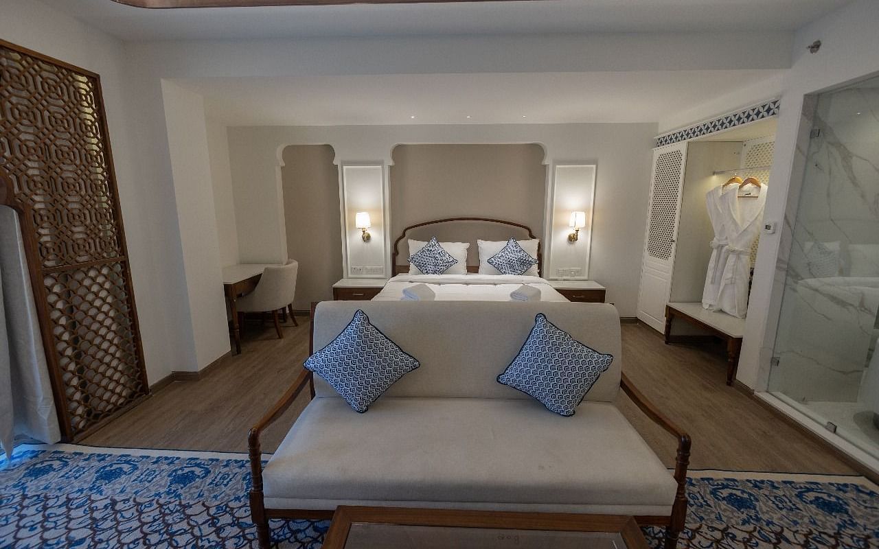 Front view shot of the Purna bedroom featuring a small couch in front of the double bed at Bhagirathi by RDB Atishay.