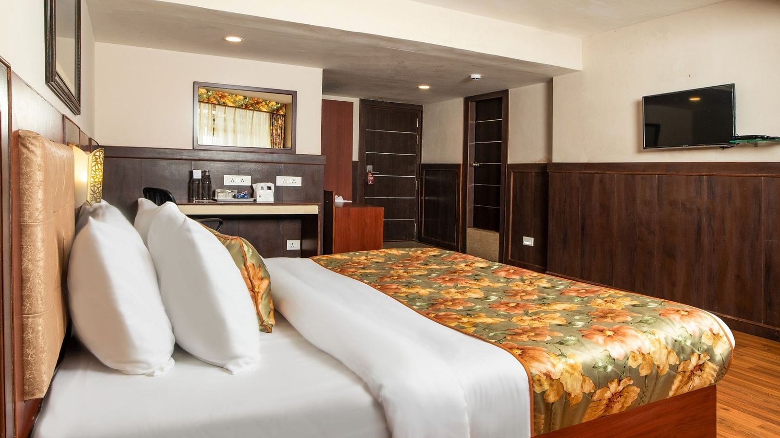 A side view of a bed in a room that has a chair and work desk along with a TV on the wall | Summit Oakden Resort & Spa, Mall Road