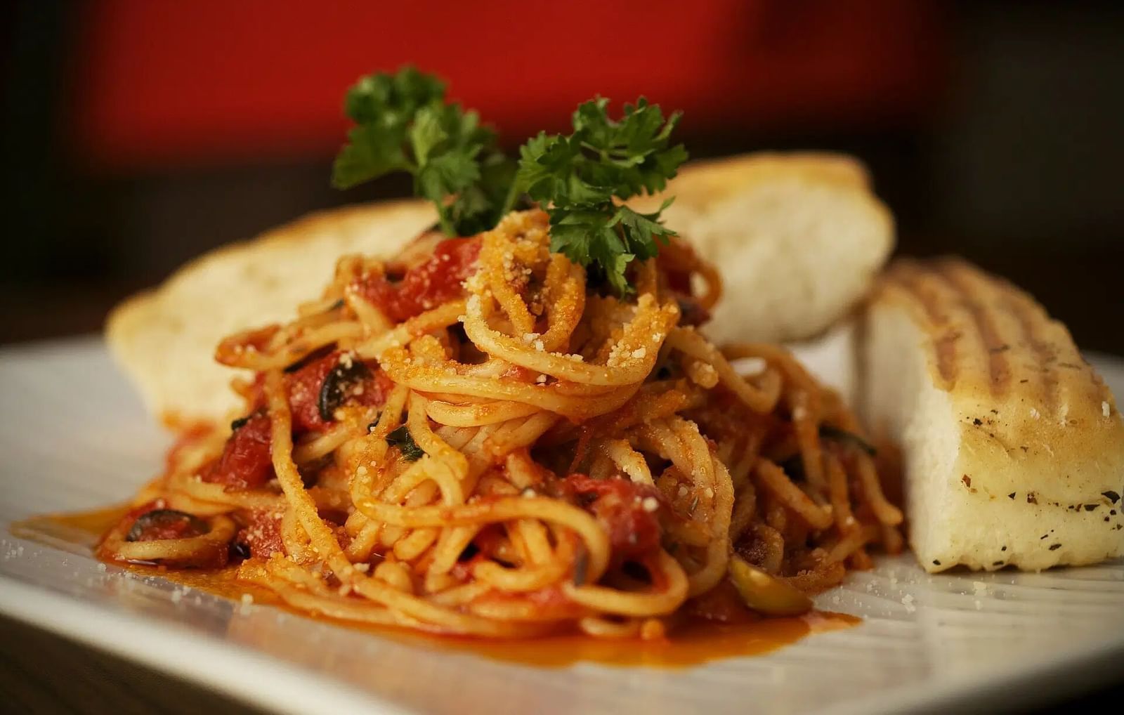 A bowl of pasta with red sauce and bread on a white plate | Altamont Court, Jamaica