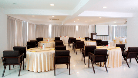 A meeting space at Springs Hotel & Spa, J.C. Road with round tables, chairs, curtains, and open floor layout.