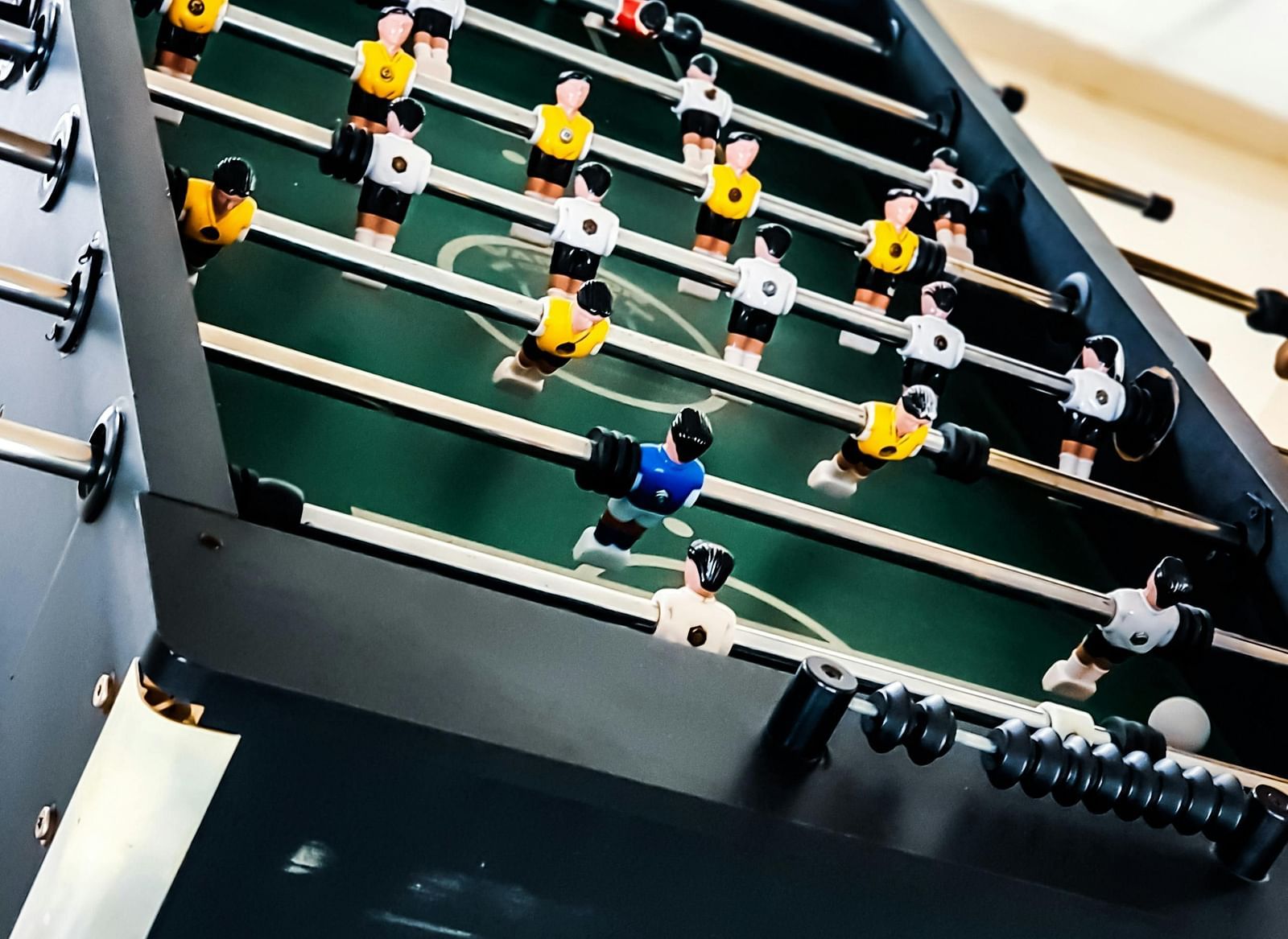 Foosball table with miniature football players arranged for a game, viewed from an angle