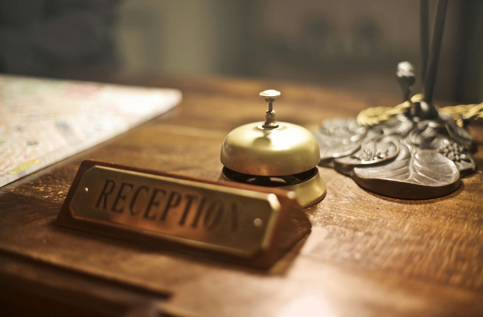 A reception desk with a bell placed on it and reception name tag also in view