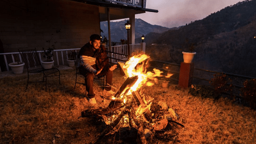 A roaring bonfire in the twilight outside of the resort, with hills visible in the distance at BluSalzz Collection - Suvaasa Resort, Ramgarh