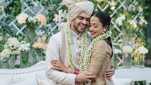 Image of a couple with garlands around their neck embracing for a photo.