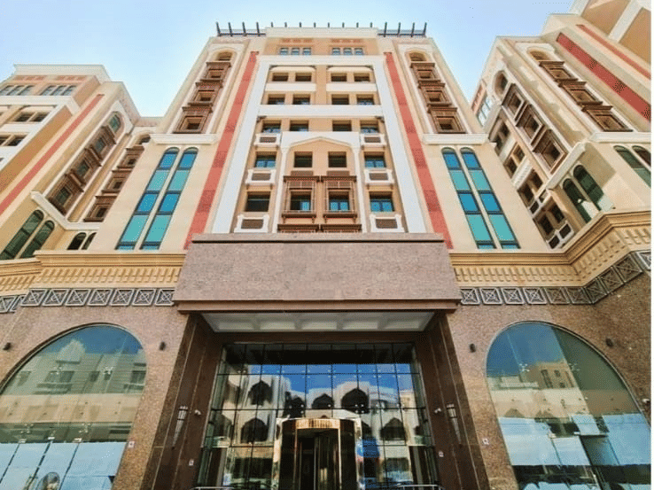 Facade view of La Maison Hotel, Doha from below with blue sky in the background.