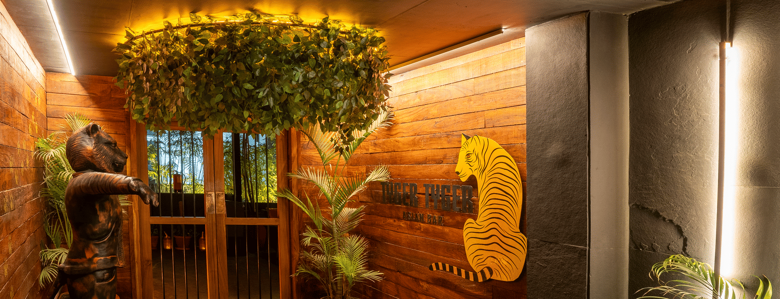 A hallway with hanging plants, wooden wall decor and green flooring at Infiniti Hotel, Indore.