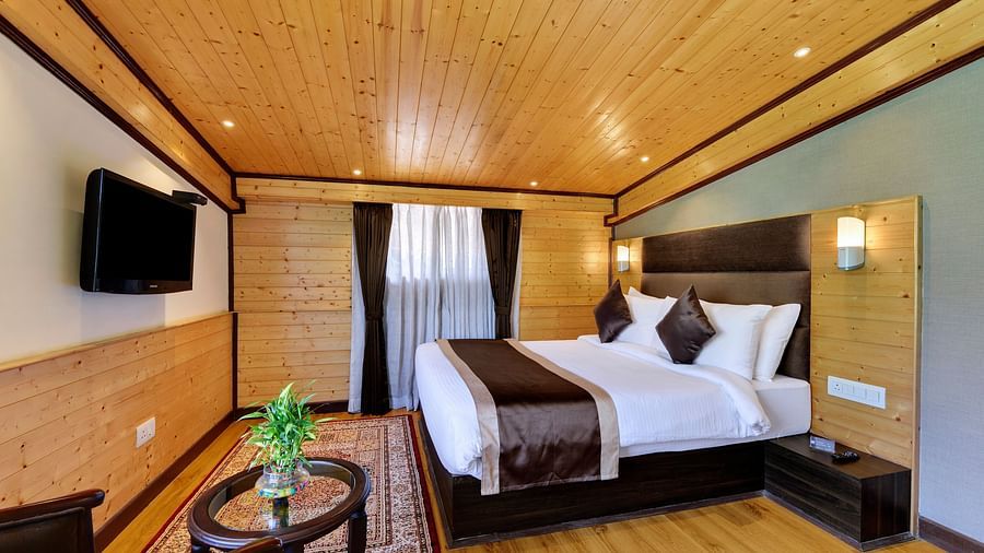 A queen bed opposite a wall mounted tv in Attic family room - Sumitel Shangrila, Deorali