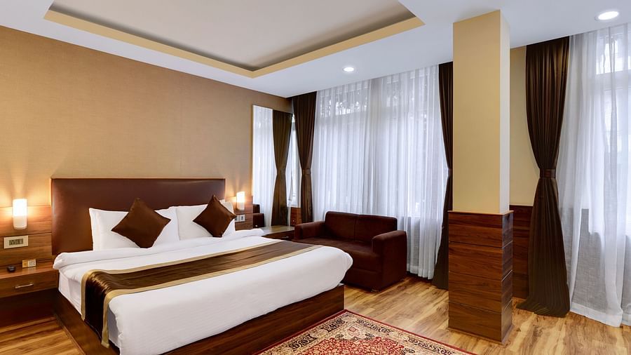 A queen bed with a sofa next to it inside Premium Room - Sumitel Shangrila, Deorali