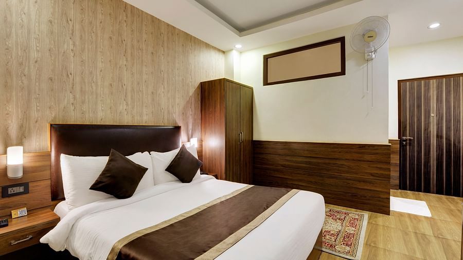 A queen bed with side tables and lamps on either side inside Deluxe Room - Sumitel Shangrila, Deorali
