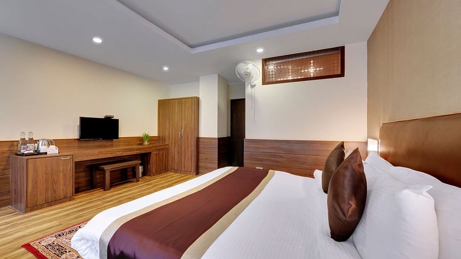 a queen bed opposite a study desk inside Deluxe Room - Sumitel Shangrila, Deorali