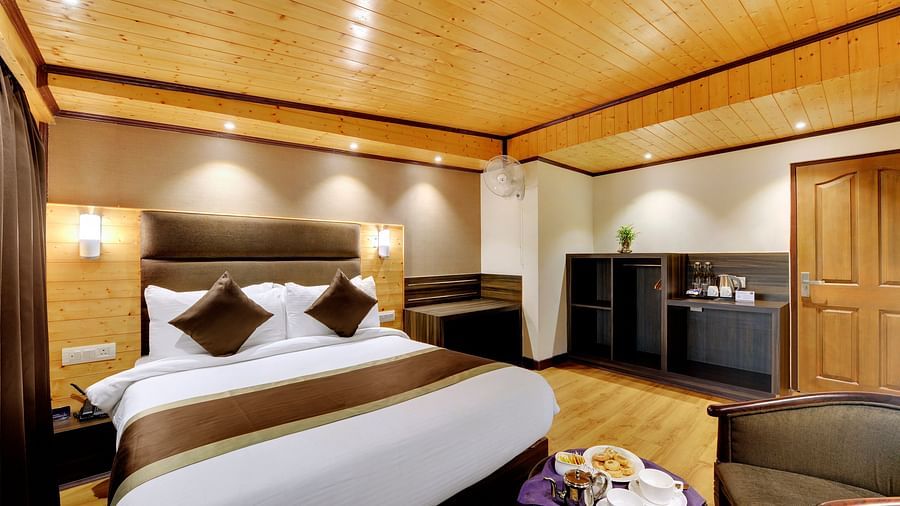 a queen bed with side table and lamps on either side inside Deluxe Room - Sumitel Shangrila, Deorali