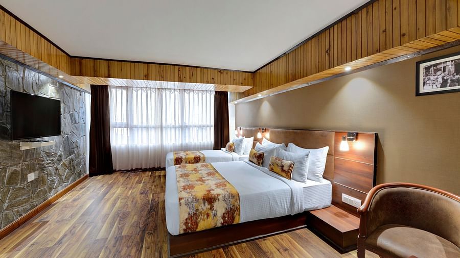 Image of a Premium Triple Room with wooden flooring, two beds and a television at Yashshree Mall Road, Darjeeling.