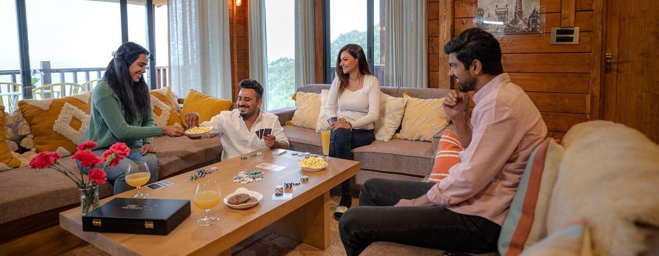An image of friends enjoying cards on a sofa at avalon cottages
