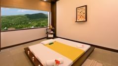 A bed on the floor with a window view of the garden inside a room at the spa - ananta udaipur