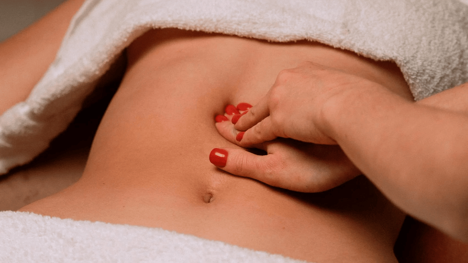 An image where the massage therapist is massaging a woman's abdomen.