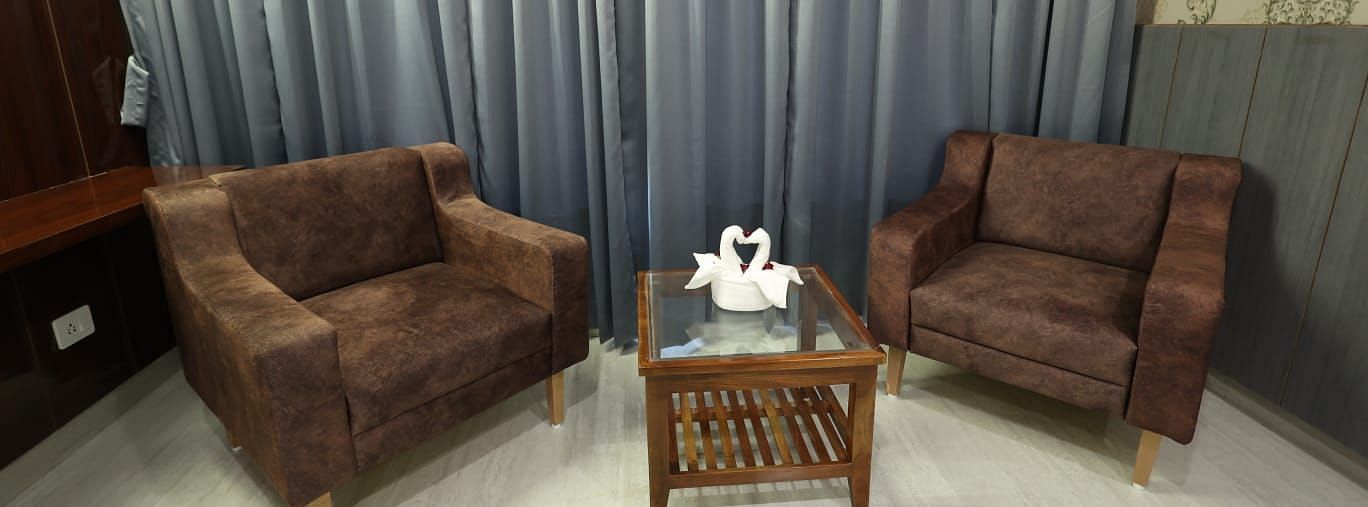 A small seating area in a room, featuring two brown plush armchairs and a small wooden table - Bamboo Saa Mulberry Resort, Pushkar