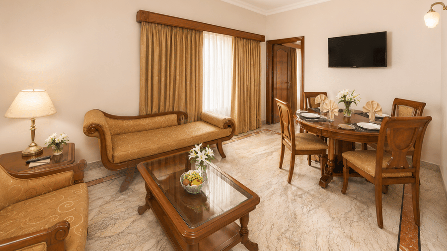 A room at Raj Park, Chennai, with sofas, tables, and a television.