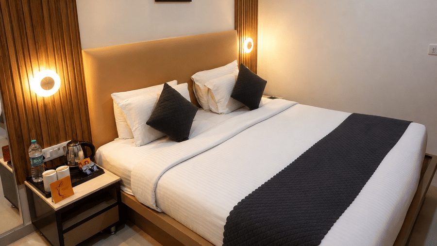 TGI Apple Inn, Ajmer Road, Jaipur | A room with a large bed, pillows, spreads, lamps, a wall art, and a table with necessities.