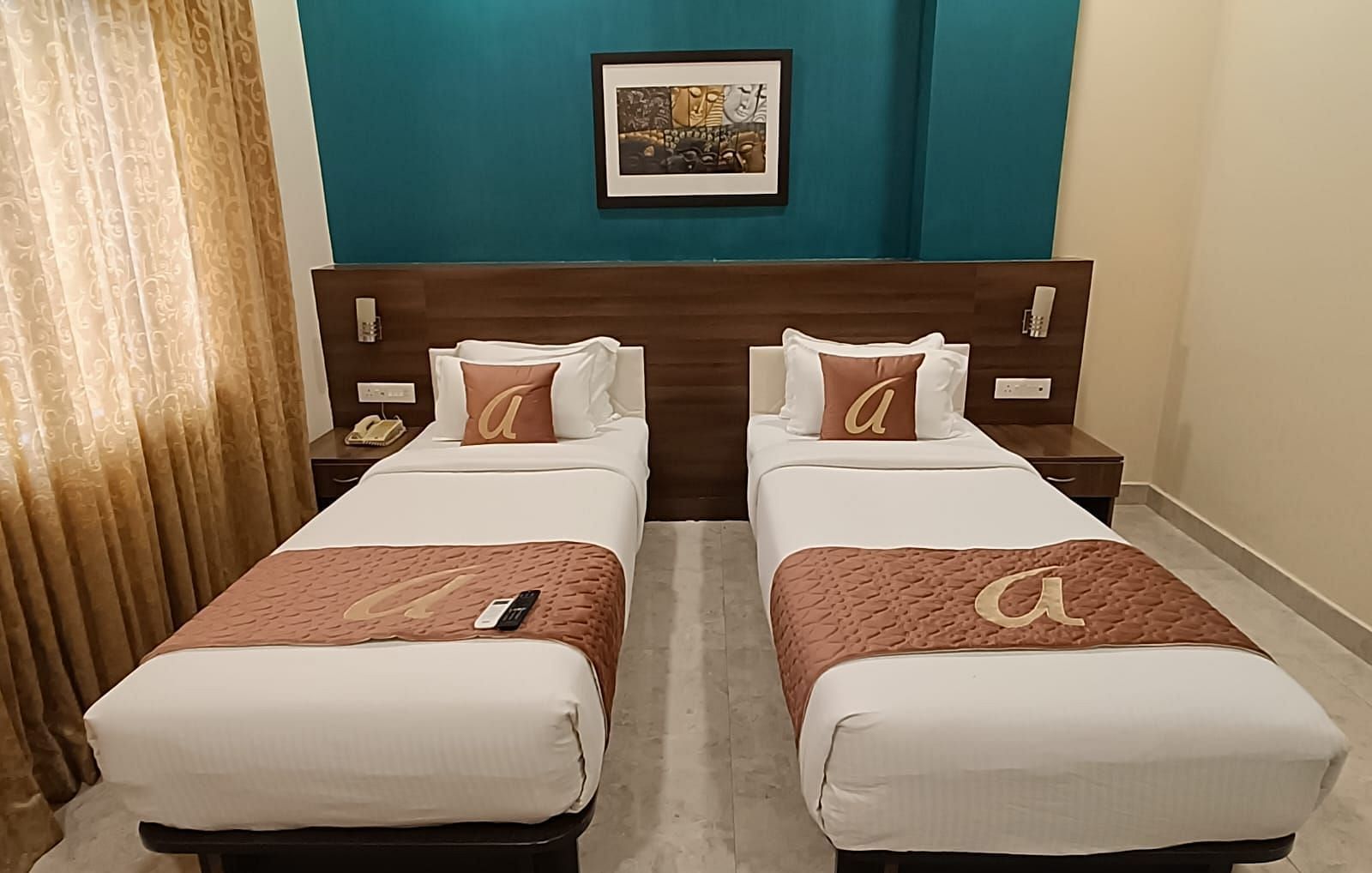 View of Twin Deluxe Room at Astra Hotels and Suites, Whitefield where two beds are arranged side by side and a image hanging on the wall in the background.