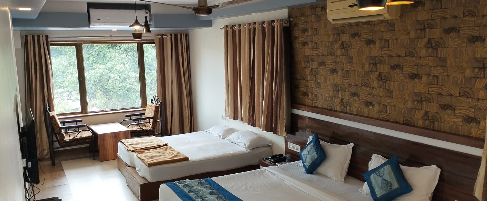 The Suite at Mountview Resort, furnished with two king size beds, a wall-mounted TV, air-conditioning, and a seating area with windows that open to the natural setting outside.
