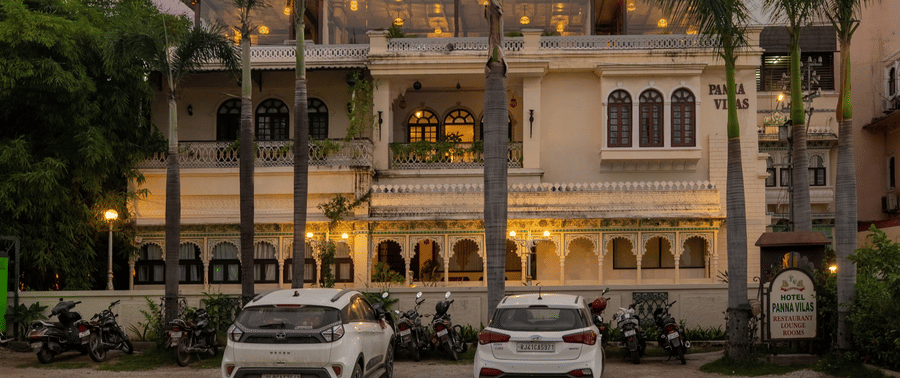 A facade of Panna Vilas Palace, featuring cars parked infront the building
