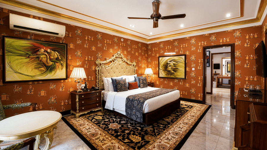 Royal Villa bedroom at Mayfair Lagoon Bhubaneswar featuring a canopied king bed, traditional wall art, chandelier, and a marble-accented seating area