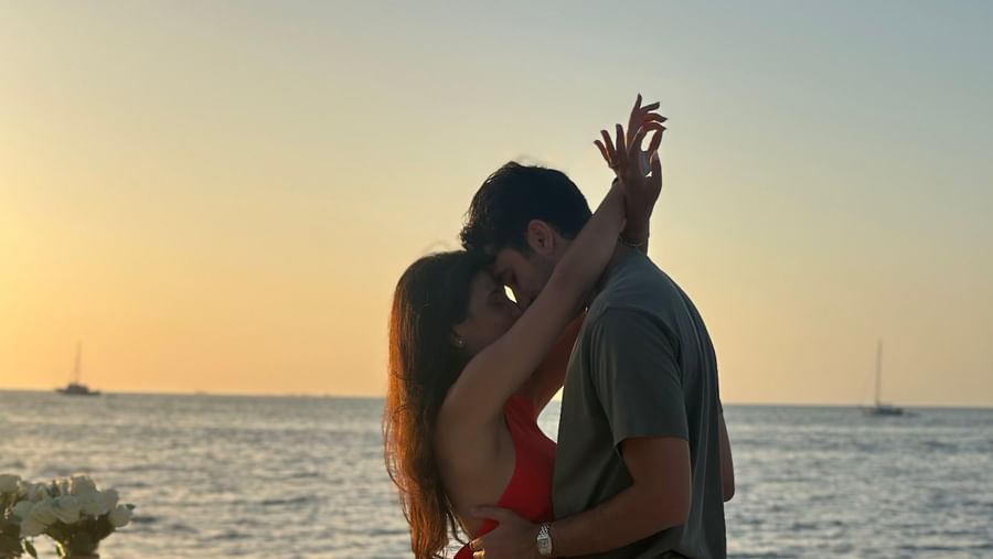 A silhouette of a couple kissing on the pier with floral decorations scattered as the sun sets over the water at Casa Morada.