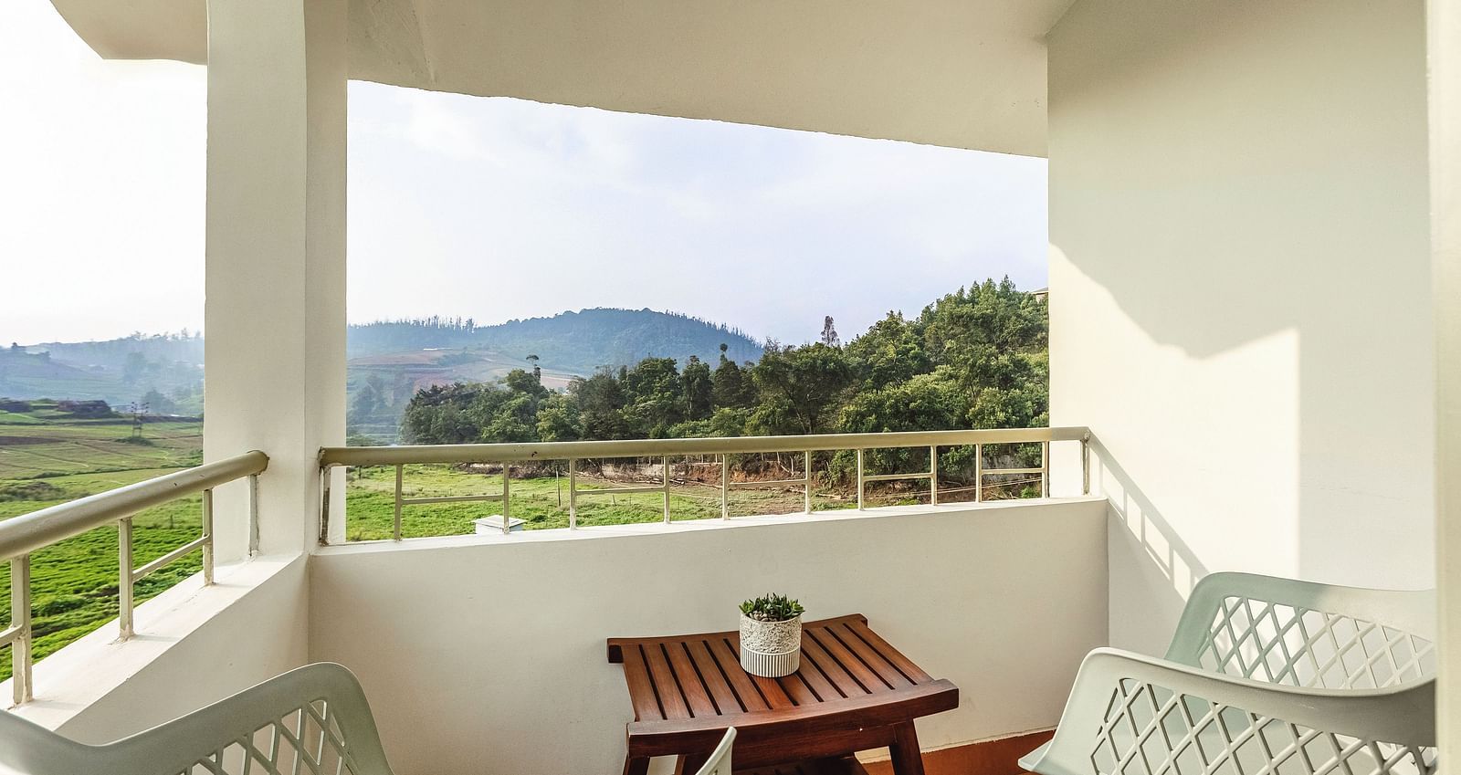 Balcony at Mango Hill Shola, Ooty, furnished with outdoor seating and a table, overlooking a peaceful landscape