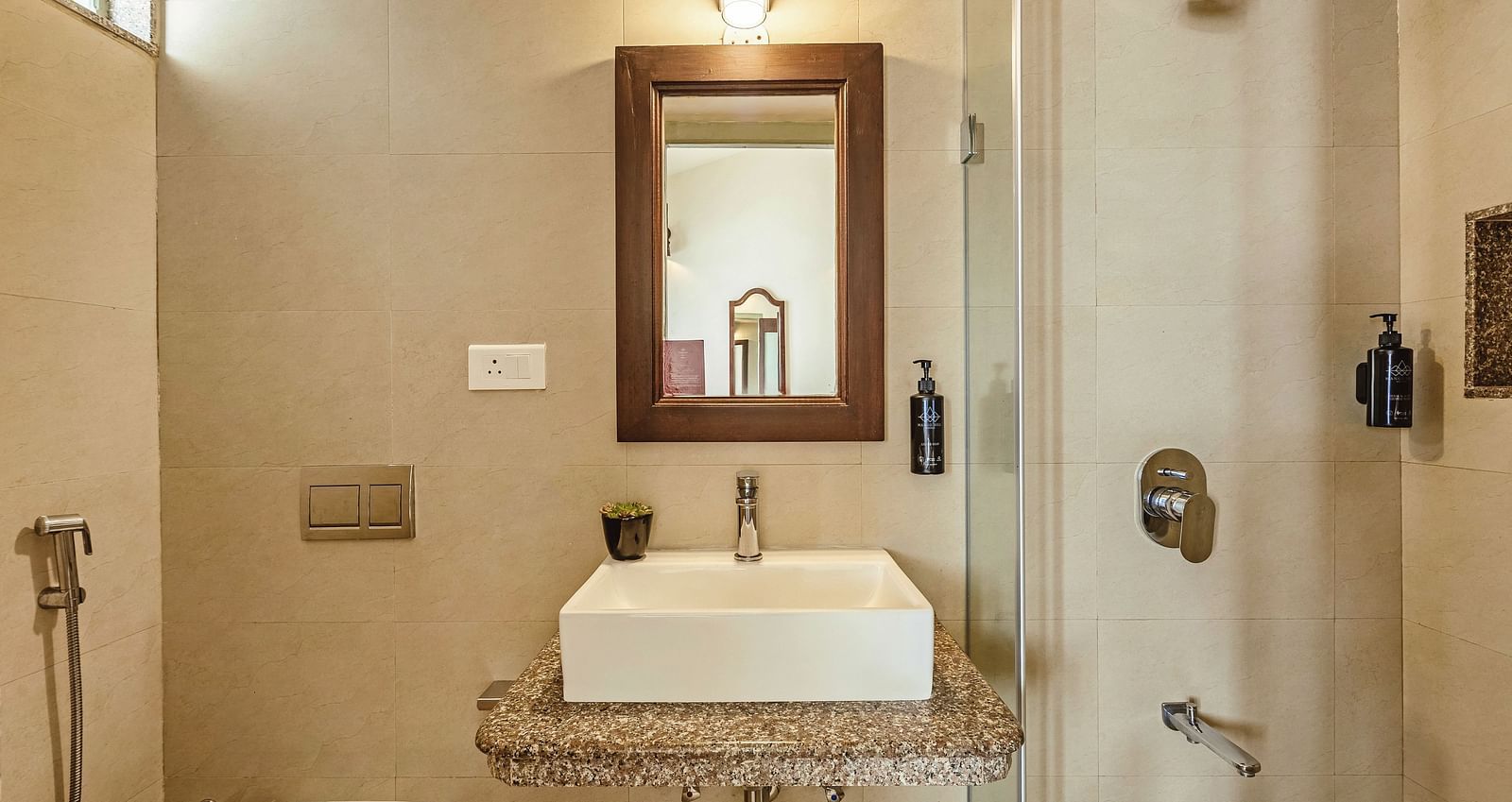 Stylish bathroom at Mango Hill Shola, Ooty, equipped with a modern sink, wall-mounted mirror, and western-style toilet, all under soft ambient lighting.