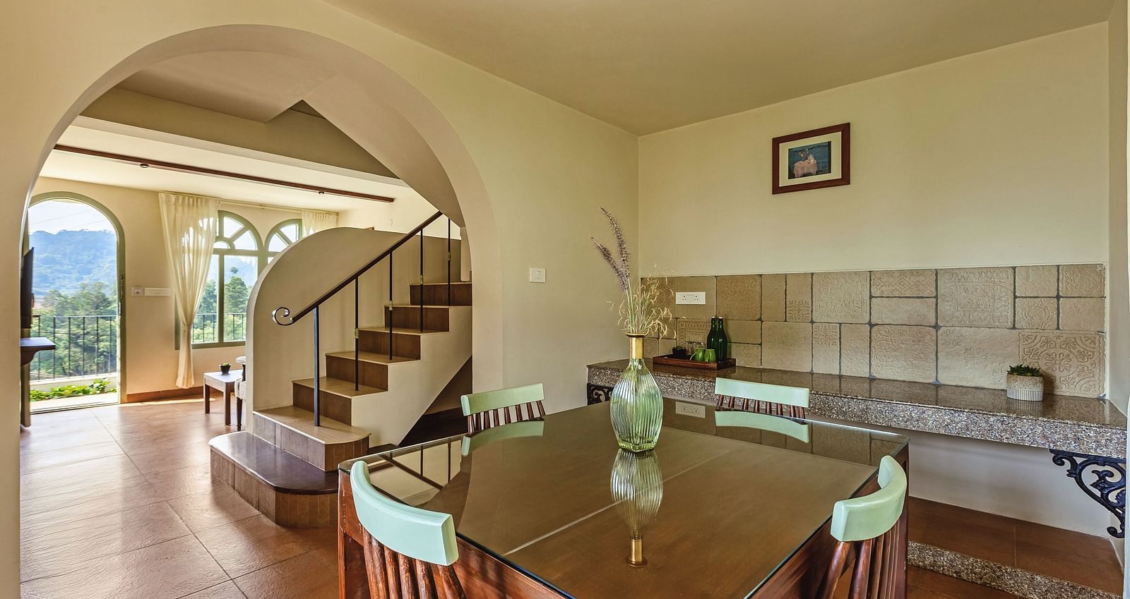 Spacious open-plan living and dining area at Mango Hill Shola, Ooty, with tiled flooring, classic furnishings, and a staircase leading to the upper level.