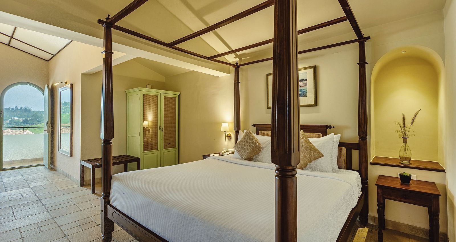 Charming bedroom at Mango Hill Shola, Ooty with an inviting four-poster bed and arched niche detail near the headboard.
