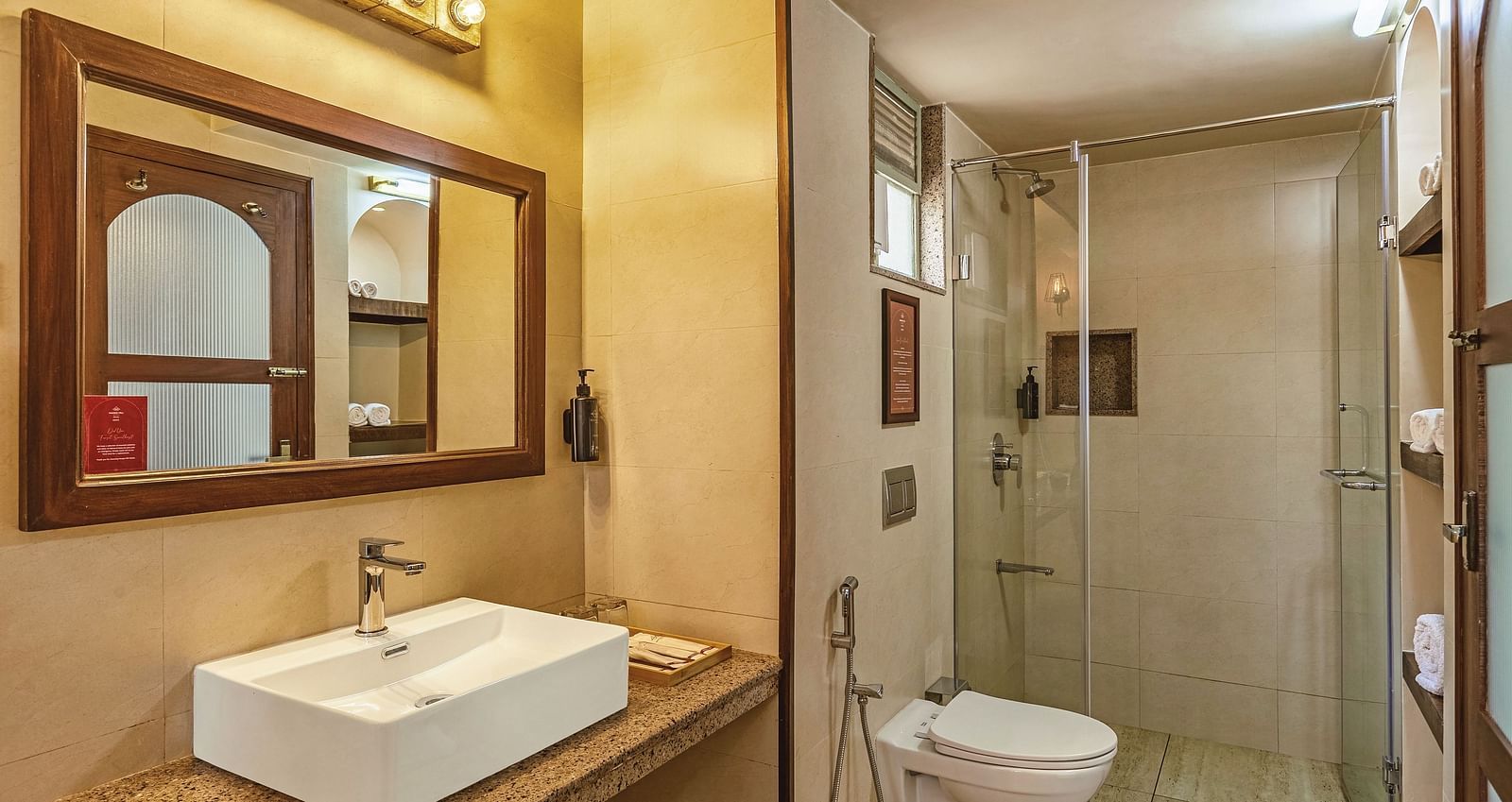 Modern bathroom at Mango Hill Shola, Ooty with a wide mirror, countertop basin, and enclosed shower area.