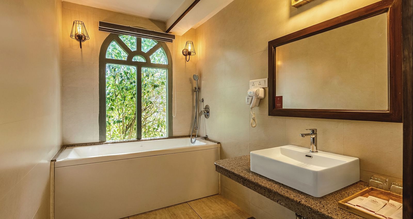 uxurious bathroom at Mango Hill Shola, Ooty featuring a deep soaking tub, wide mirror, and warm ambient lighting.