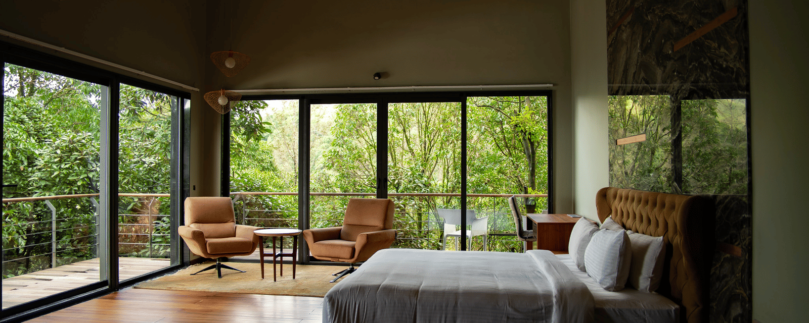 A spacious bedroom at Stanley Revelation with a vaulted ceiling, floor-to-ceiling windows, and a balcony.