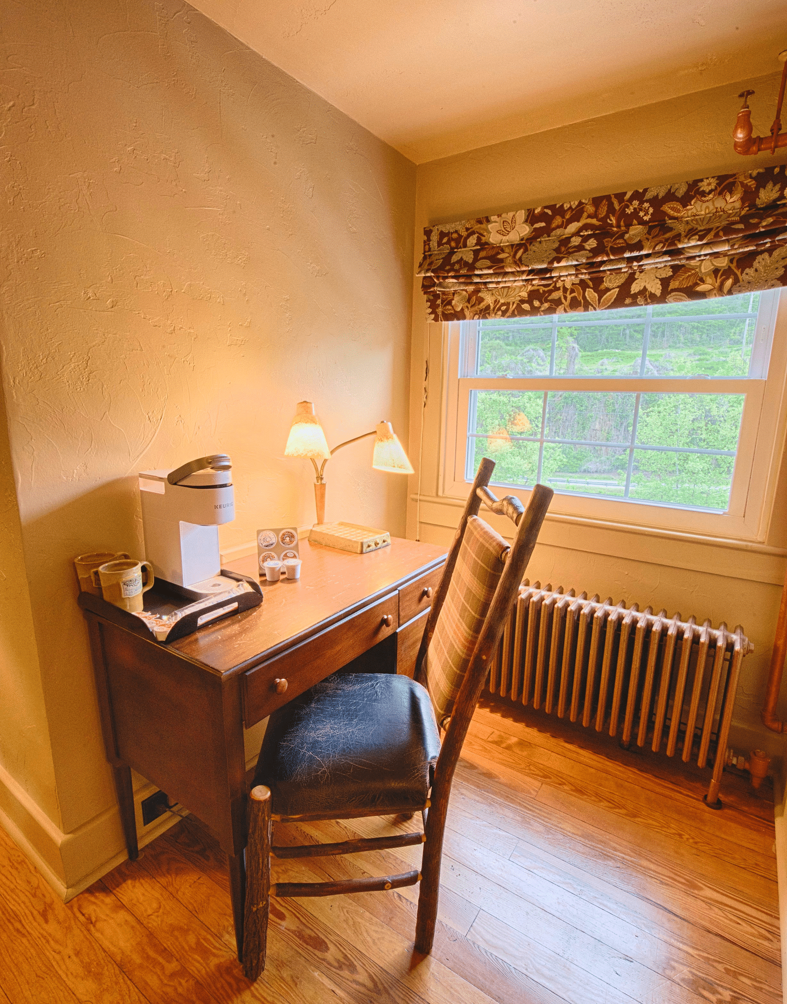 a writing desk and chair along with a table lamp kept besides a window - Historic Tapoco Lodge