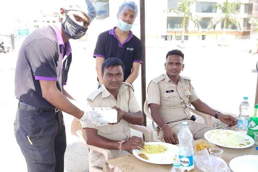 two staff members giving something to the police while posing for a picture - VITS Hotels & Resorts