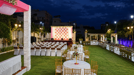 Banquet tables and chairs are set up on a lawn beneath a dark twilight sky - Lords Inn Sangam, Bhopal
