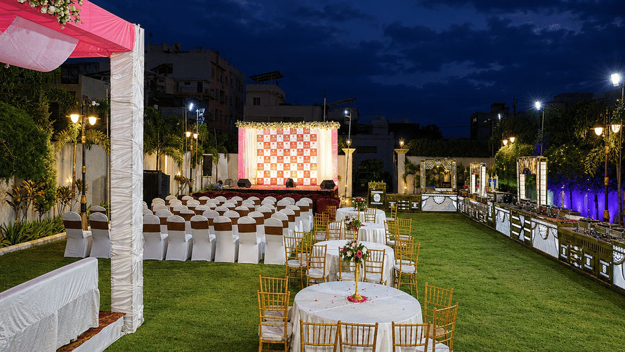 Banquet tables and chairs are set up on a lawn beneath a dark twilight sky - Lords Inn Sangam, Bhopal