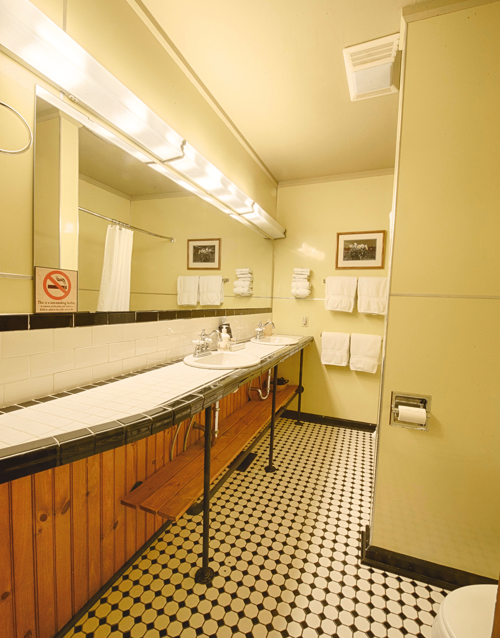 a bathroom featuring a wide mirror and a wash basinfull view image of a bedroom with wooden interiors featuring two beds - Historic Tapoco Lodge