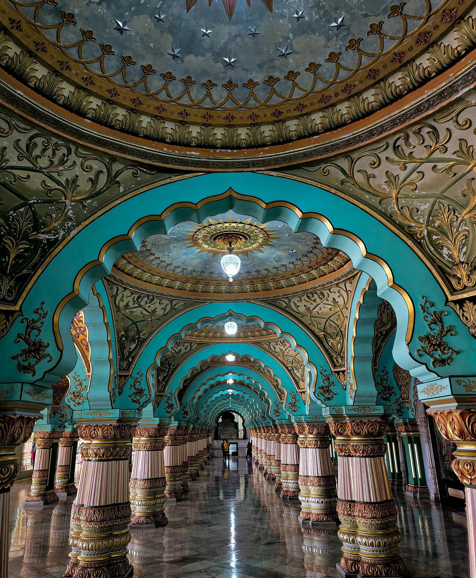 The ornate and colourful interior archways of a historical building with intricate designs and a reflective floor