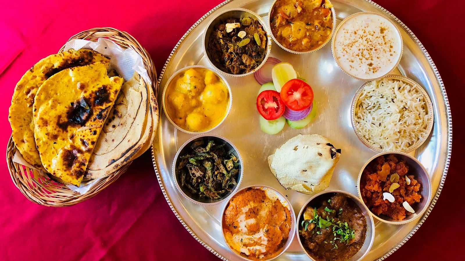 A colorful Indian thali with various dishes in small bowls in a plate.
