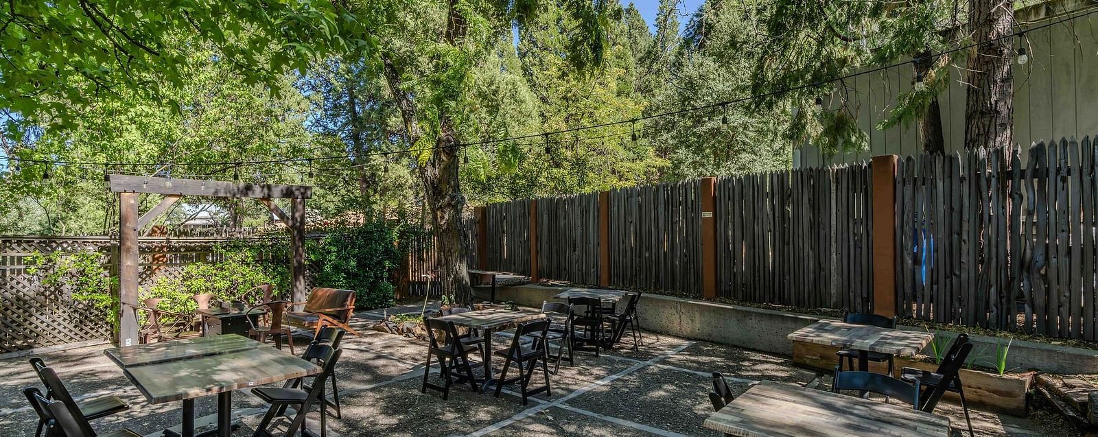 A backyard with a dining arrangement surrounded by trees - The Groveland Hotel.