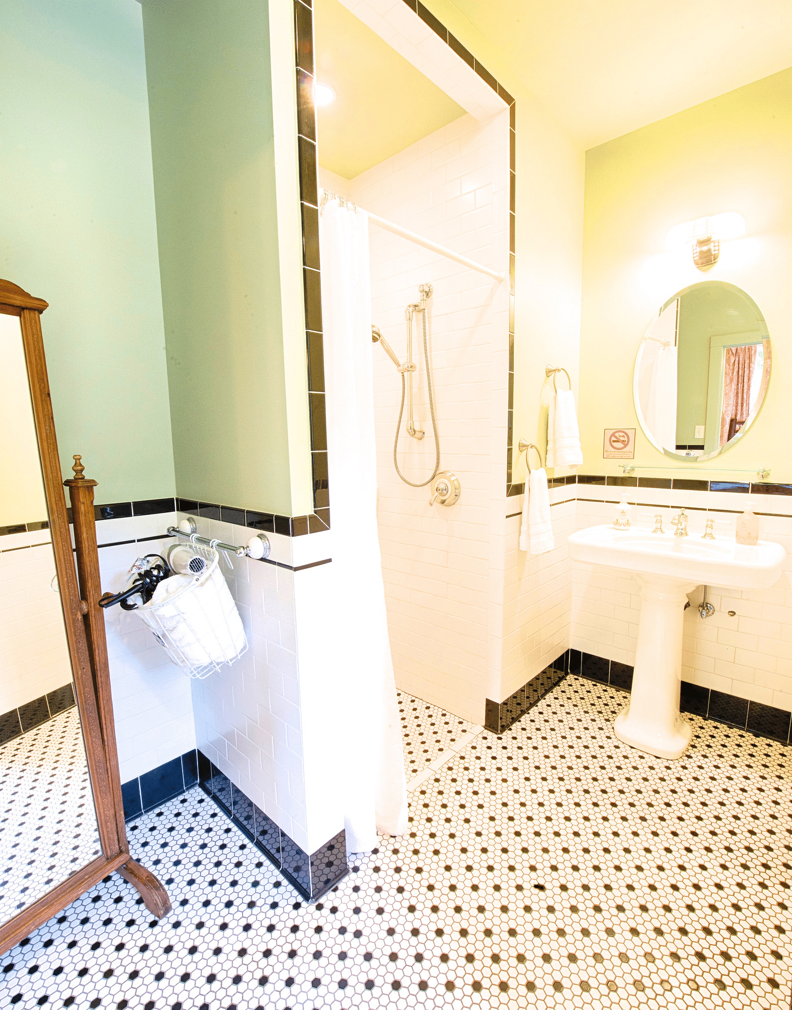 a bathroom with black and white patterned tiles along with a wash basin at the far end of the bathroom - Historic Tapoco Lodge