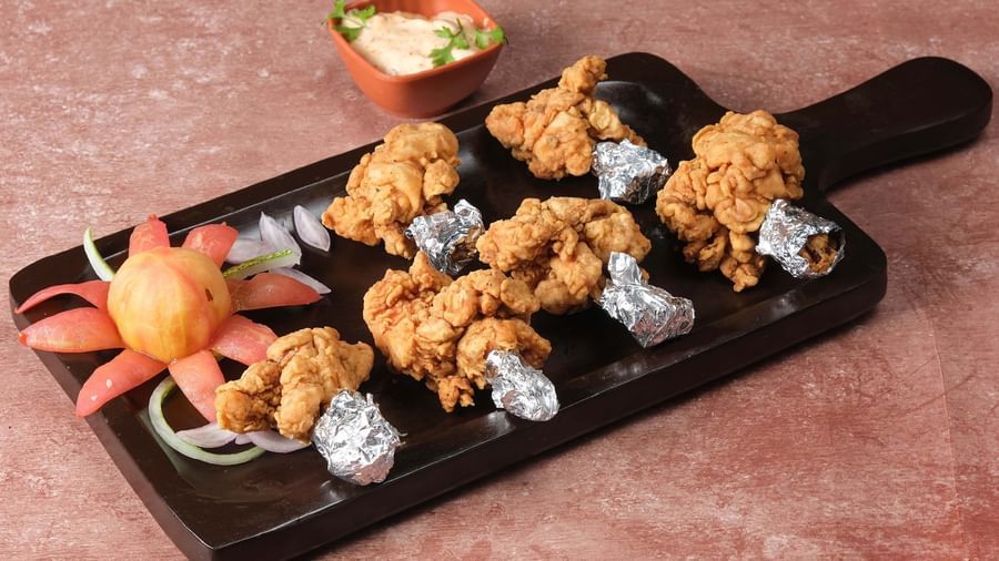 Drumsticks served on a plate with decoration by the side with salad at Monday Hotels Amalapuram Heights.