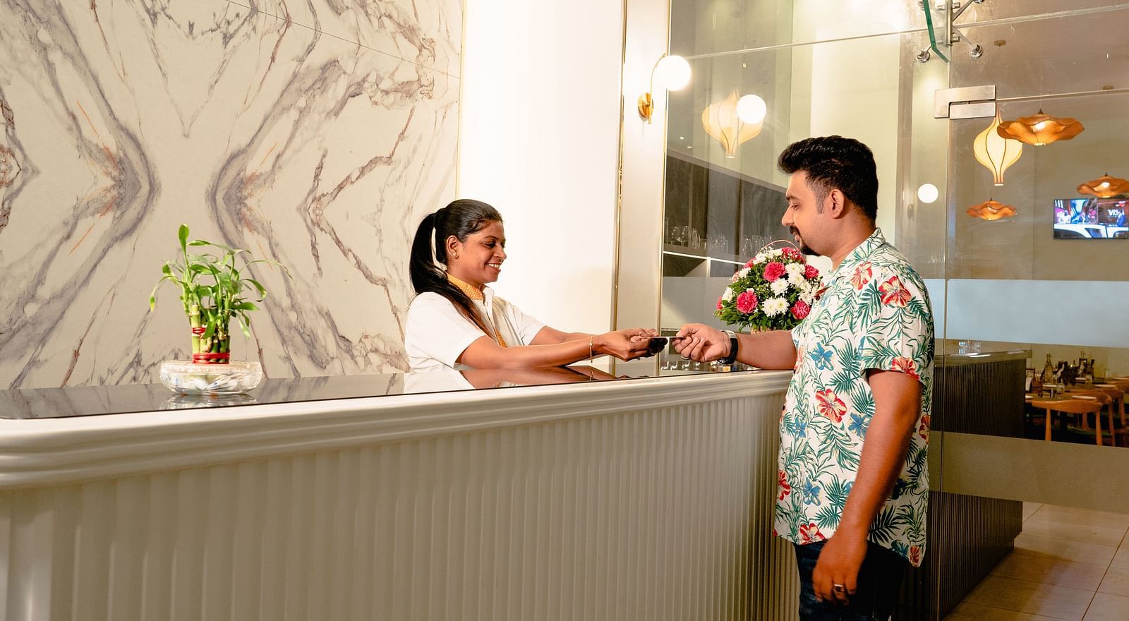 A man and a woman exchanging a card at a hotel reception - TGI Ameya Grand, Goa