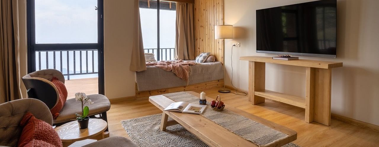An image of a room with flat TV screen, seating space and a centre table | Avalon Cottages, Kanatal