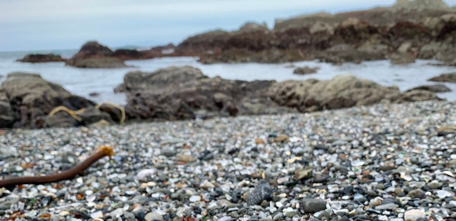 A close up image of glass stones and other rolling stones near the beach