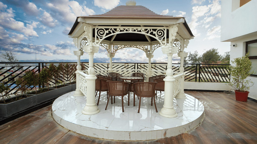 An open-air gazebo seating area at Shanti Seaview Resort & Spa overlooking the sea with elegant chairs and wooden deck flooring.
